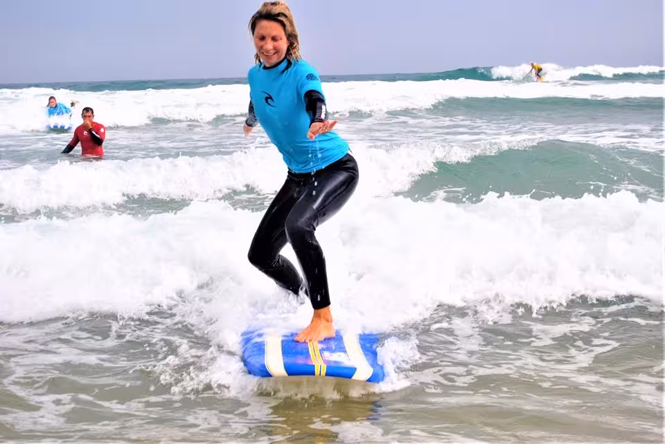 Smiling woman riding waves on a surfboard during an expert surf lesson on the Aljezur coast Portugal
