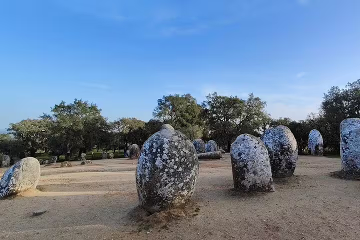 Ancient megalithic stones at Almendres Cromlech, Évora, under a clear blue sky, highlight the cultural tour to Évora and Monsaraz.