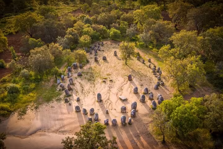 Aerial view of Almendres Cromlech prehistoric stone circle in Évora, surrounded by lush greenery, perfect for guided tours.