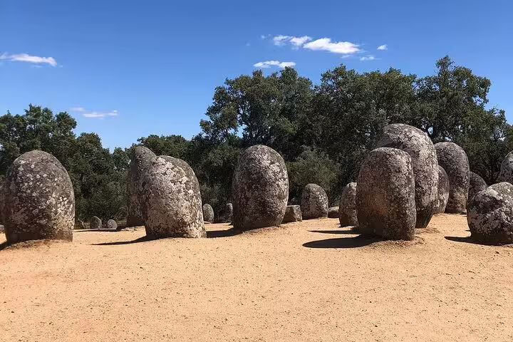 Ancient standing stones under a clear blue sky in the Almendres Cromlech, a highlight of the Évora Essencials full-day tour from Lisbon.