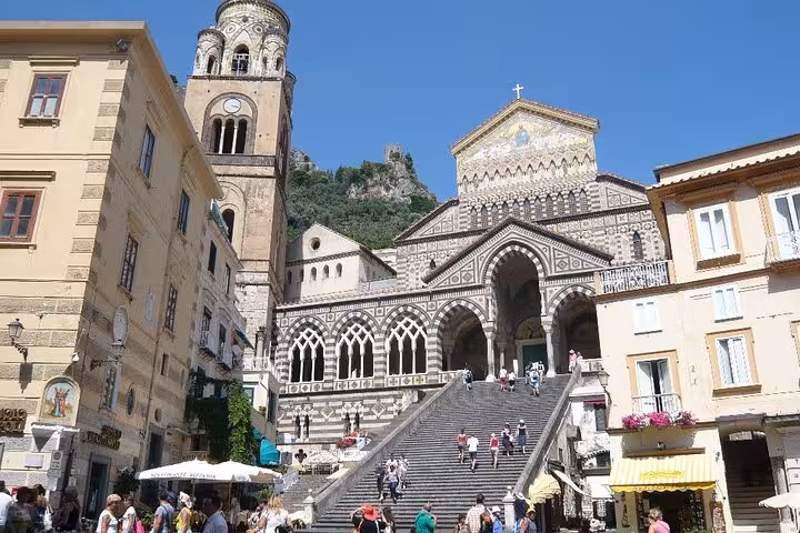 Historic Amalfi Cathedral facade with intricate architecture and tower under clear blue skies on the Amalfi Coast.