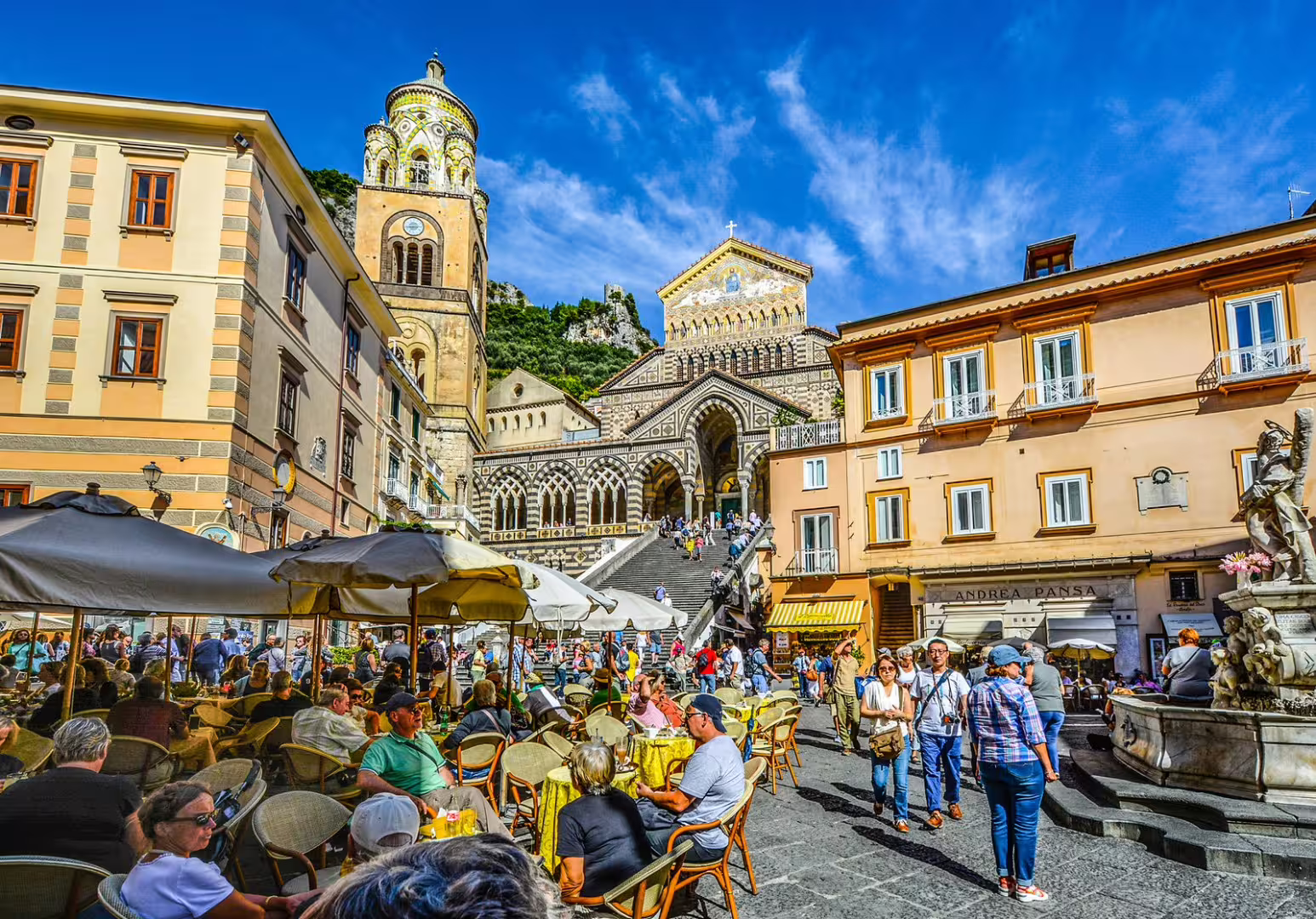 Bustling Piazza del Duomo in Amalfi with cafes and the stunning Amalfi Cathedral, a highlight of the minivan tour.