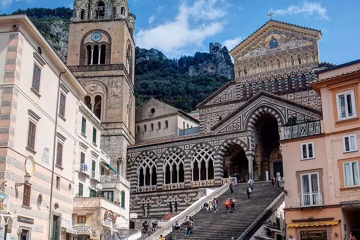 The stunning Amalfi Cathedral with intricate architecture and steps, framed by lush hills, is a highlight of the tour.