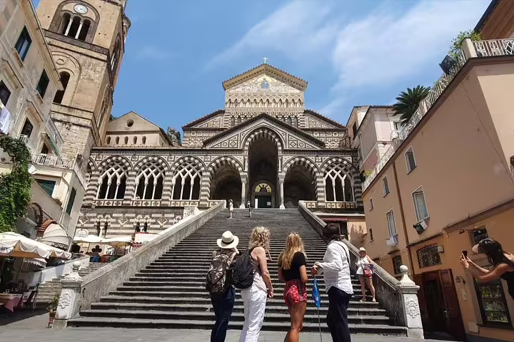 Visitors admire the stunning facade of Amalfi Cathedral, a highlight on tours from Sorrento to the Amalfi Coast.