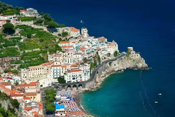 Aerial view of Amalfi town clinging to cliffs above turquoise sea on a shared Amalfi Coast private tour along the scenic road