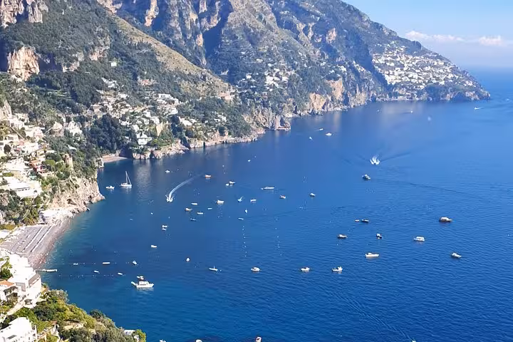 Stunning aerial view of Amalfi Coast's turquoise waters with boats and rugged cliffs near Sorrento.