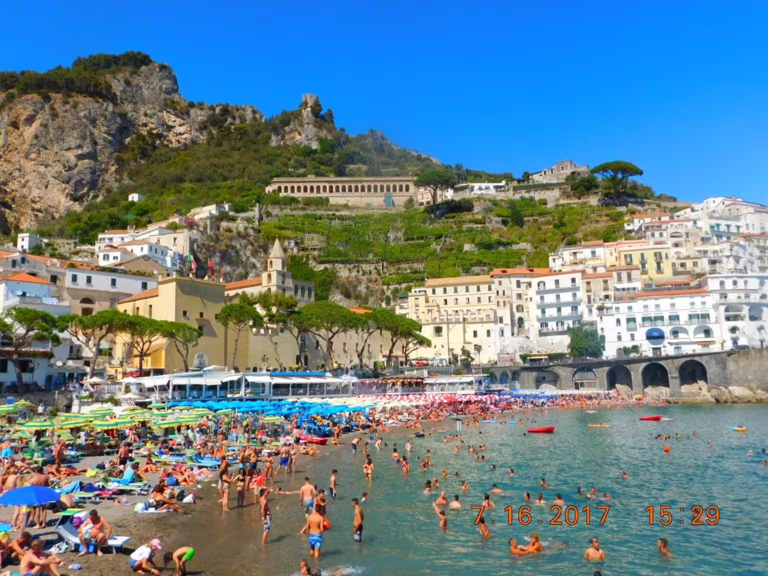 Amalfi Coast beach in Amalfi town with colorful umbrellas and cliffside houses on group tour from Naples