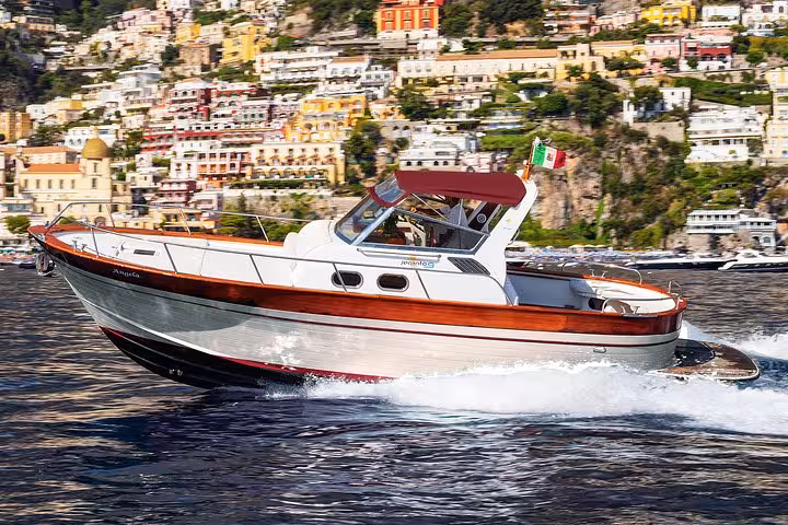 Elegant boat cruising past the vibrant coastal town of Positano on an exclusive Amalfi Coast experience.