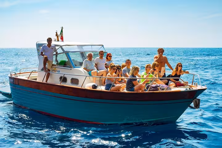 Group enjoying a sunny Amalfi Coast boat tour on crystal blue waters near Naples.