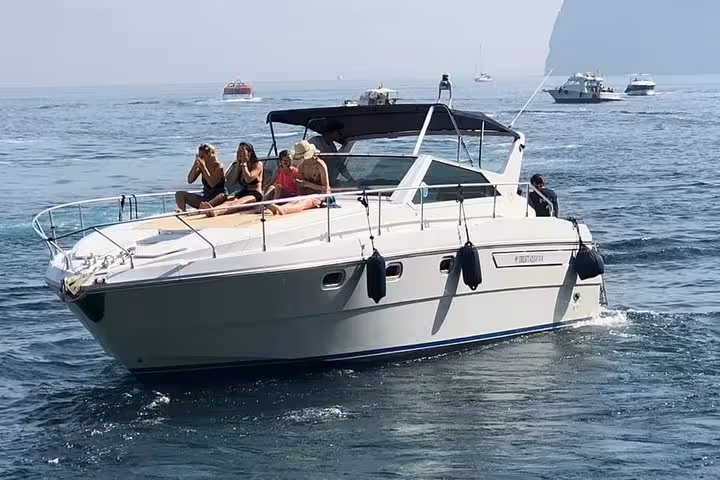 Tourists relaxing on a yacht during a scenic boat tour along the Amalfi Coast on a sunny day.