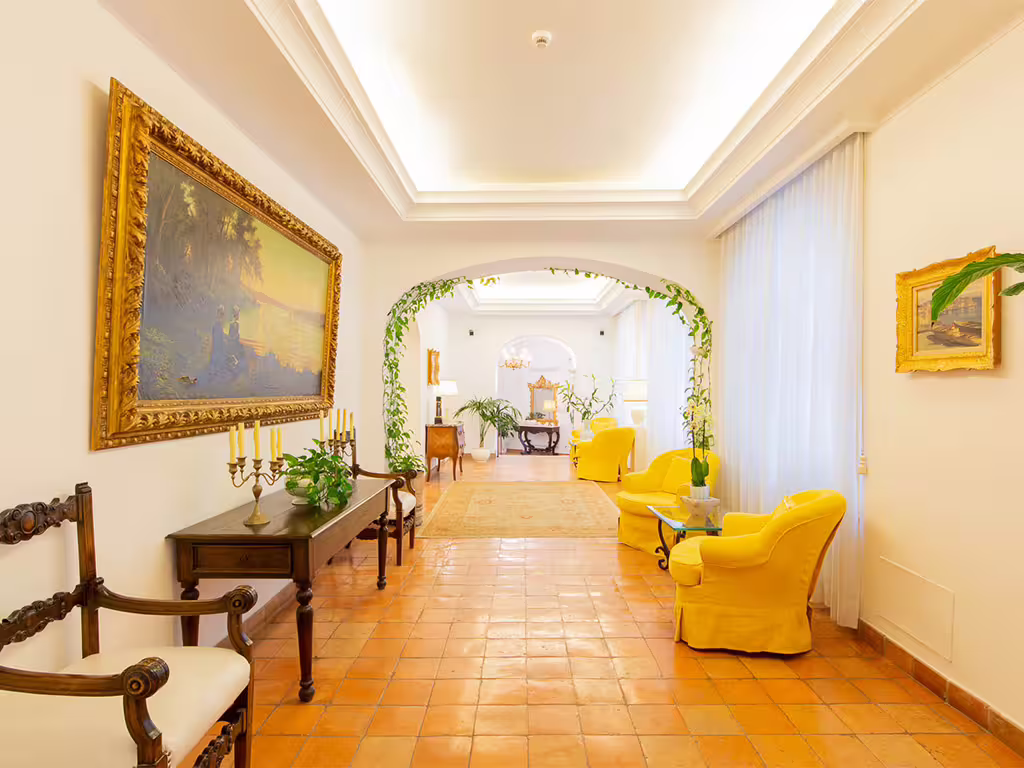 Elegant Amalfi Coast boutique hotel lounge with yellow armchairs, classic art and bright Mediterranean-style décor