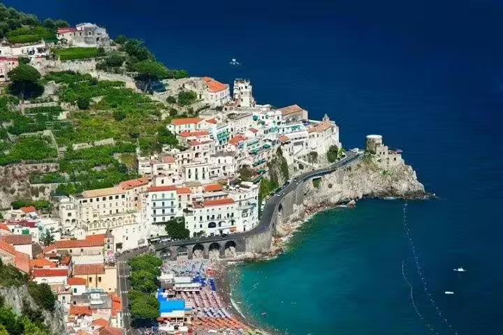 Clifftop view of Amalfi Coast village with terraced hills, coastal road and turquoise bay on a private shore excursion tour