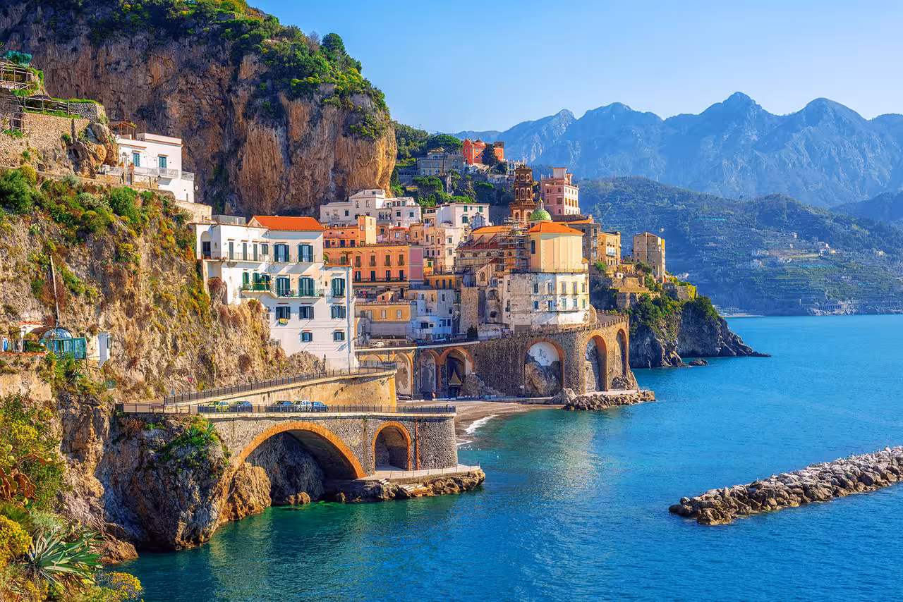 Colorful coastal buildings perched on cliffs with turquoise waters, showcasing the breathtaking Amalfi Coast scenery.