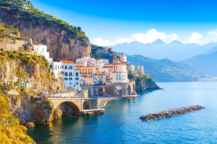 Scenic view of colorful cliffside buildings along the Amalfi Coast, bathed in sunlight with clear blue sea.