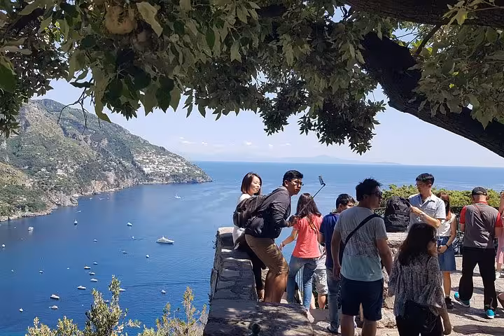 Travelers at Amalfi Coast viewpoint overlooking blue sea, part of Sorrento and Positano day tour from Rome