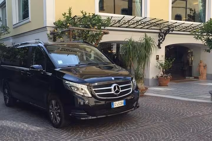 Luxury minivan parked outside a charming Italian villa, ready for Amalfi Coast small-group tour with light lunch.