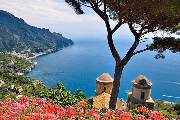 Breathtaking view of Amalfi Coast with vibrant flowers, sea, and historic architecture on a small-group minivan tour.