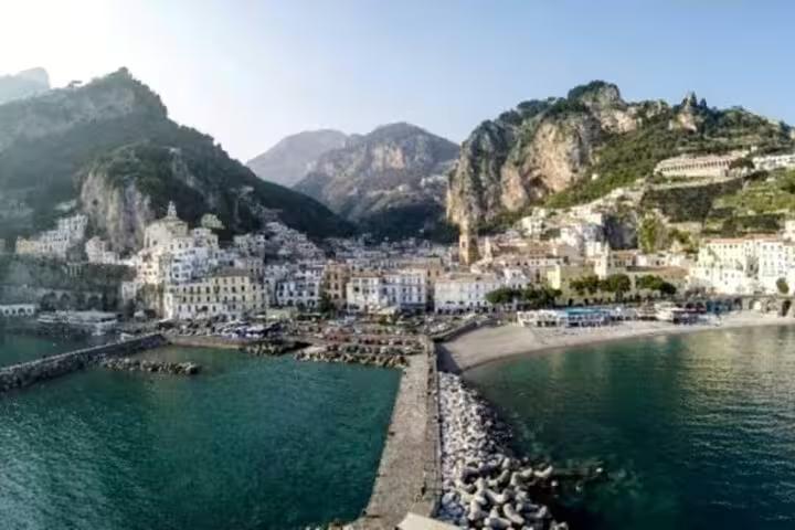 Panoramic view of Amalfi town and harbor with cliffs and turquoise sea, coastal stop on shared tour from Ravello to Positano