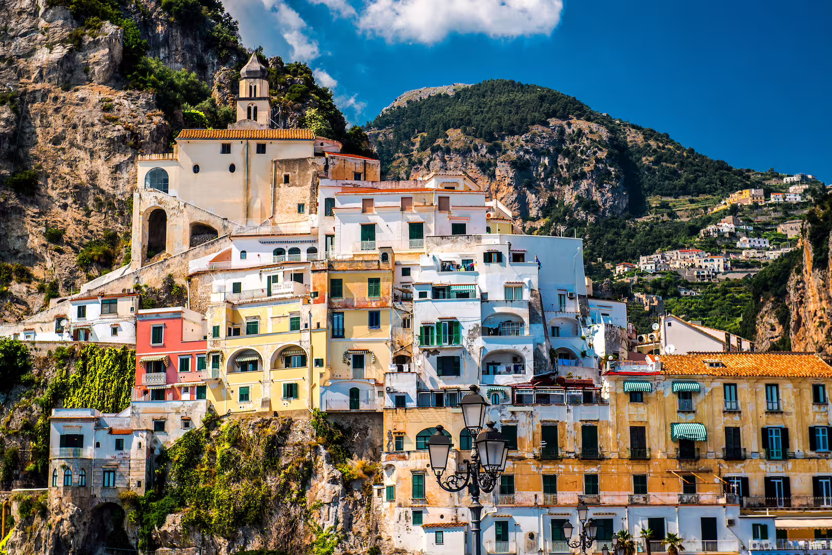 Colorful cliffside buildings in Amalfi, Italy, showcasing stunning coastal architecture and mountain backdrop.
