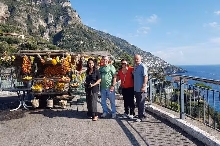 Travelers by a roadside fruit stand with sea views on Amalfi Coast day trip from Rome to Positano