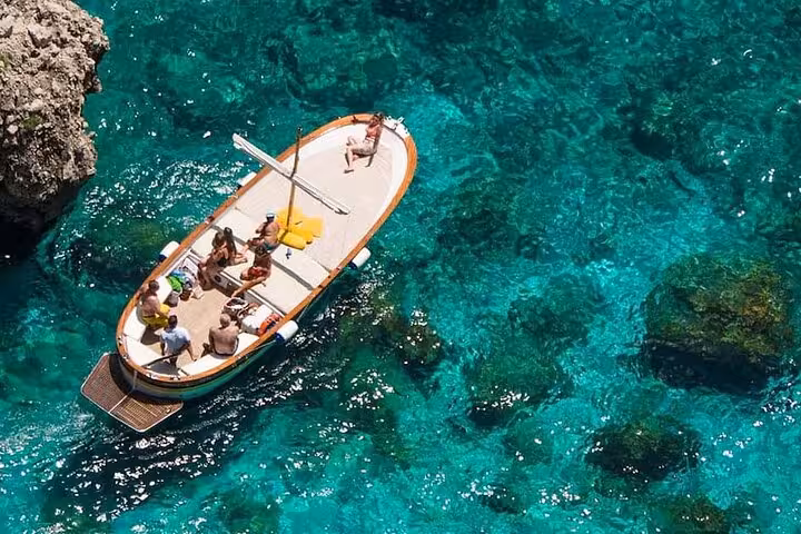 Aerial view of tourists enjoying a private boat tour on the crystal-clear waters of the Amalfi Coast.
