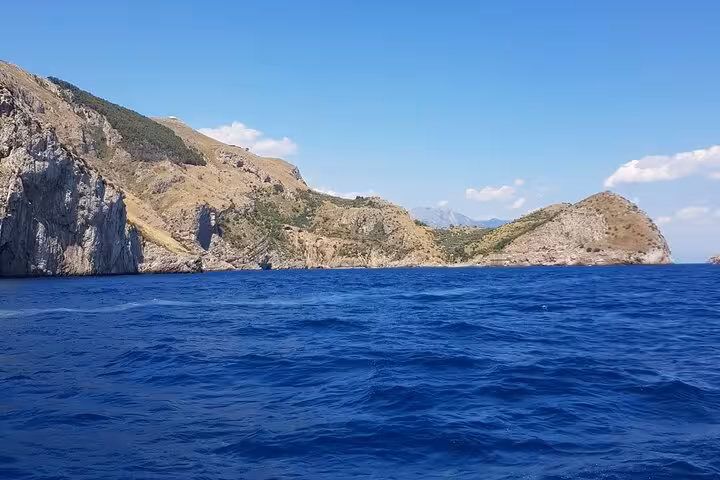 Stunning view of the rugged Amalfi Coast cliffs against a clear blue sky from a private boat tour.