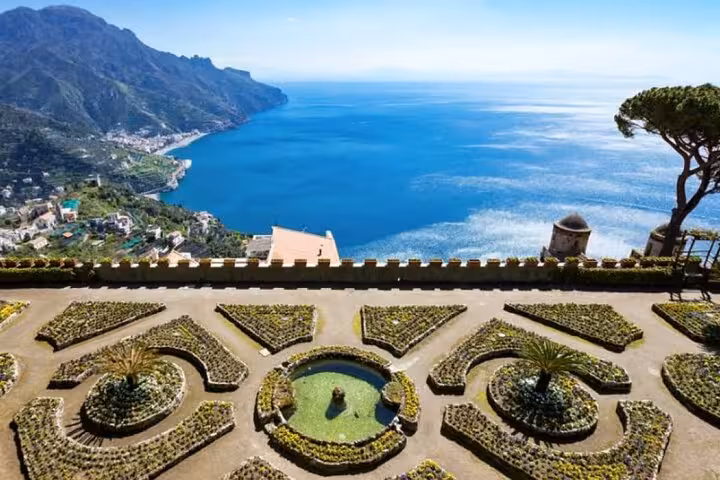 Panoramic view of Amalfi Coast from a garden terrace in Ravello, highlighting intricate landscaping and the azure sea.