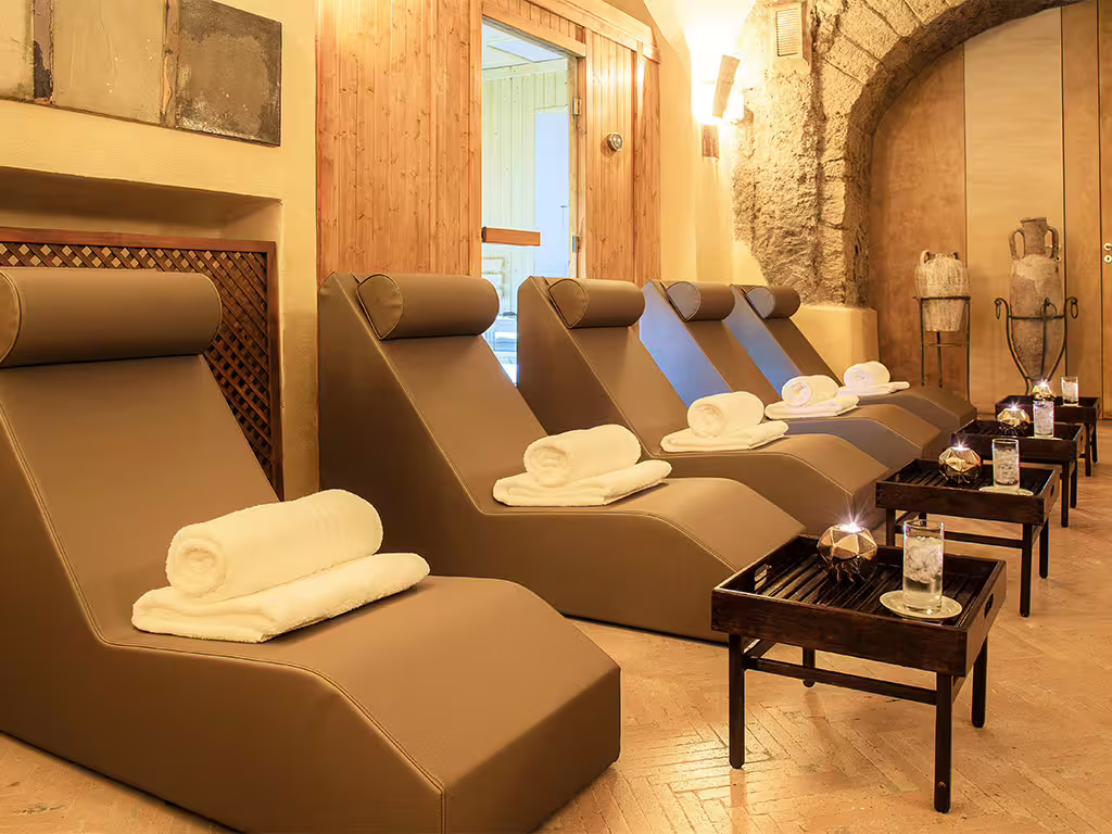 Cozy Amalfi Coast spa relaxation room with plush loungers, rolled towels and candlelit ambiance for a romantic wellness escape