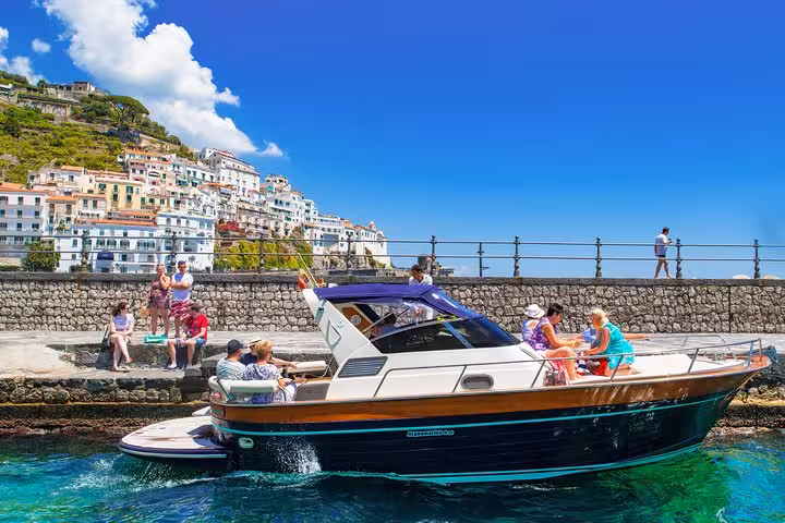 Explore the charming Amalfi Coast on a small-group boat tour, docking near vibrant seaside towns under a bright sky.