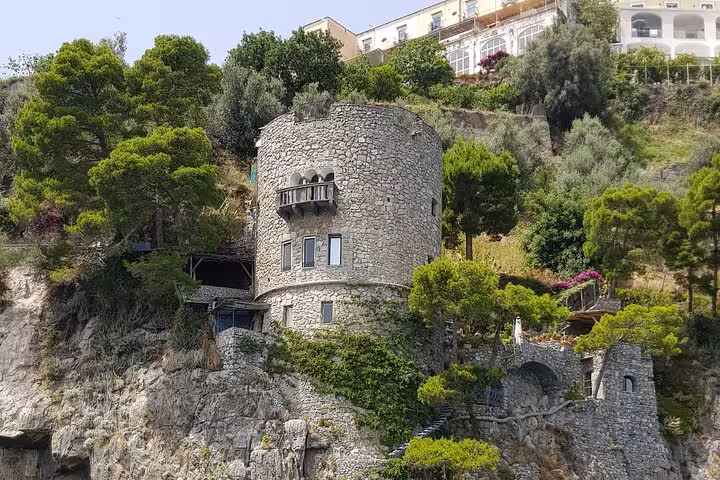 Charming stone tower nestled among lush greenery on the Amalfi Coast, viewed from a private boat tour.