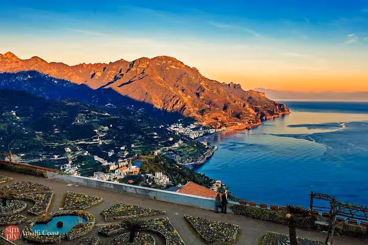 Breathtaking sunset view of the Amalfi Coast from Ravello, highlighting the majestic mountains and azure sea.