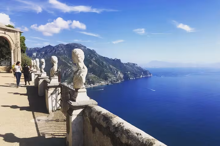 Scenic Amalfi Coast terrace with classical statues overlooking the deep blue sea on a sunny day tour.