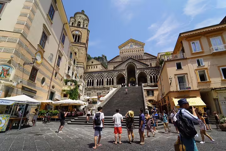 Tourists exploring Amalfi's iconic cathedral and bustling square, a highlight of the Amalfi Coast tour from Sorrento.