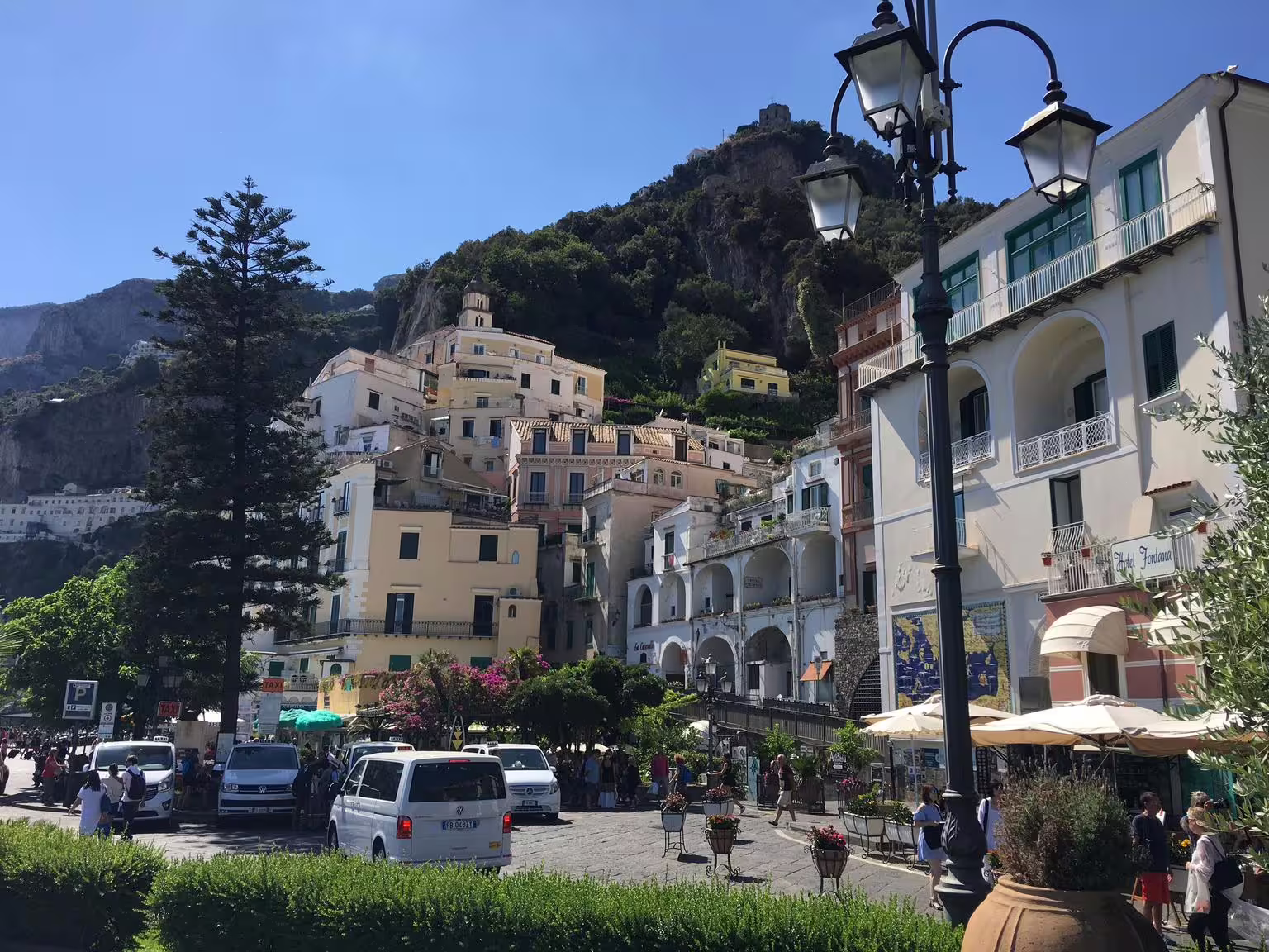 Amalfi Coast town square with hillside buildings and street lamps, stop on Pompeii and Amalfi tour from Naples