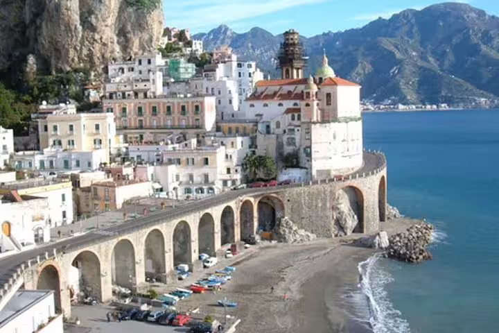 Historic Amalfi village with arched seaside road, church and beach viewed from a cruise ship shore excursion