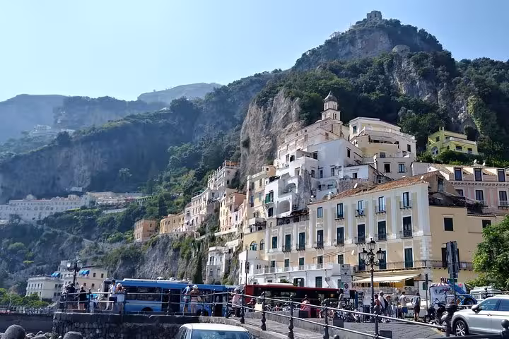 Amalfi town waterfront with pastel buildings below cliffs, on full-day Rome tour to Amalfi Coast