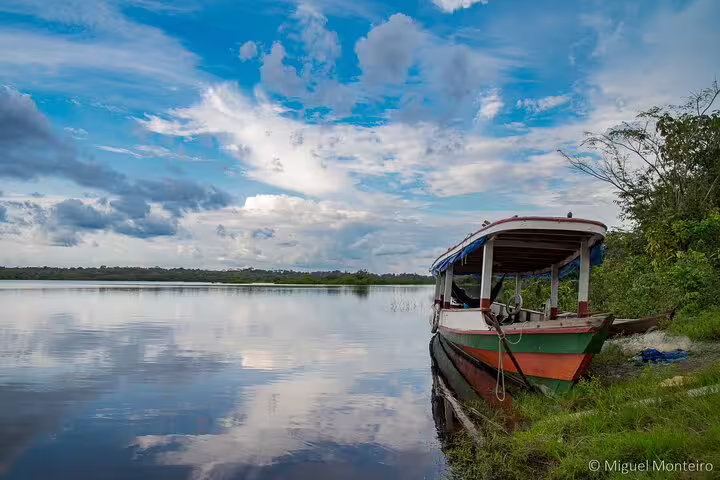 Traditional boat docked by Amanã Lake under a vast, dramatic sky, inviting exploration on the Amazon Deep Survival Trip.