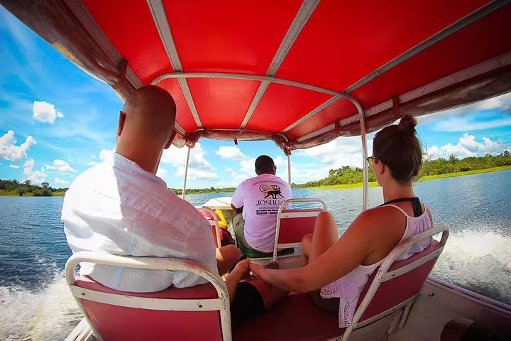 Visitors enjoy a boat ride under a red canopy, surrounded by breathtaking Amazonian landscapes at Amazon Mamori Lodge.