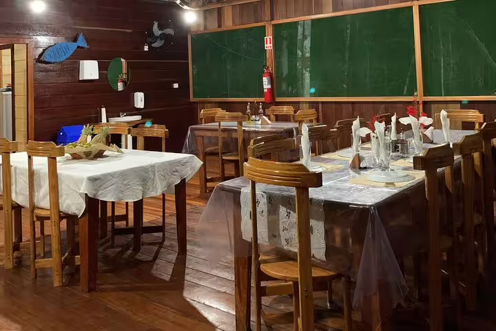 Cozy dining area at Amazon Mamori Lodge with wooden tables set for a meal, perfect for Amazon Jungle adventure.