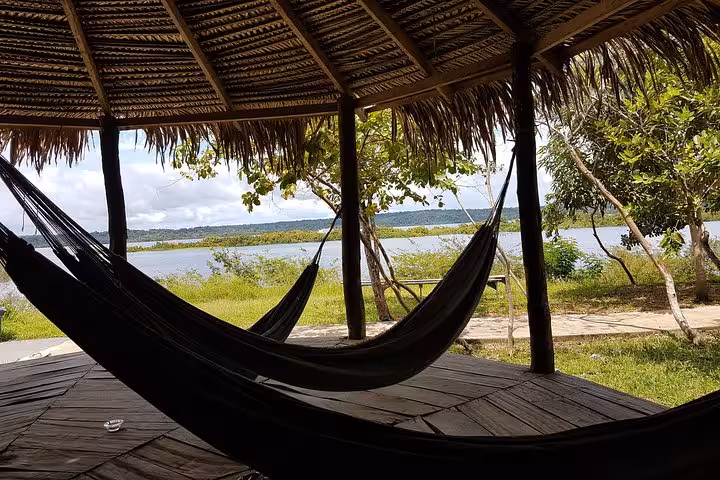 Riverside jungle lodge hammocks under thatched roof, relaxing stop on 6-day Amazon Jungle Adventure Tour