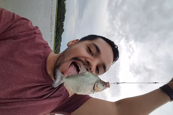 Traveler poses with a freshly caught Amazon piranha on Solimões River fishing adventure near Manaus