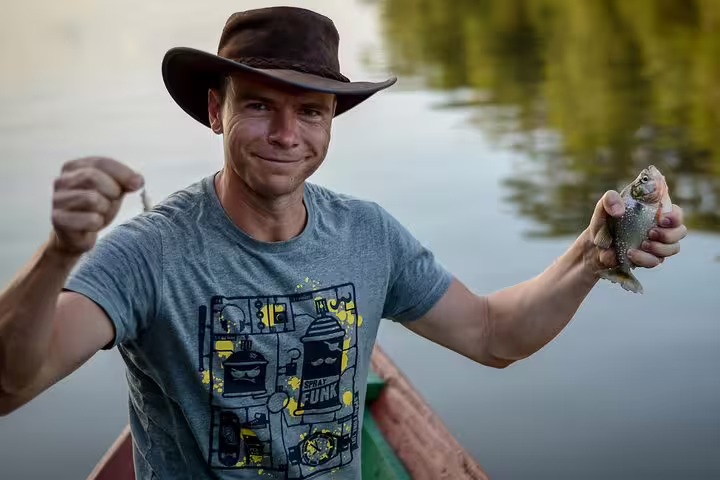 Man holding a freshly caught fish while boating on the Amazon River.