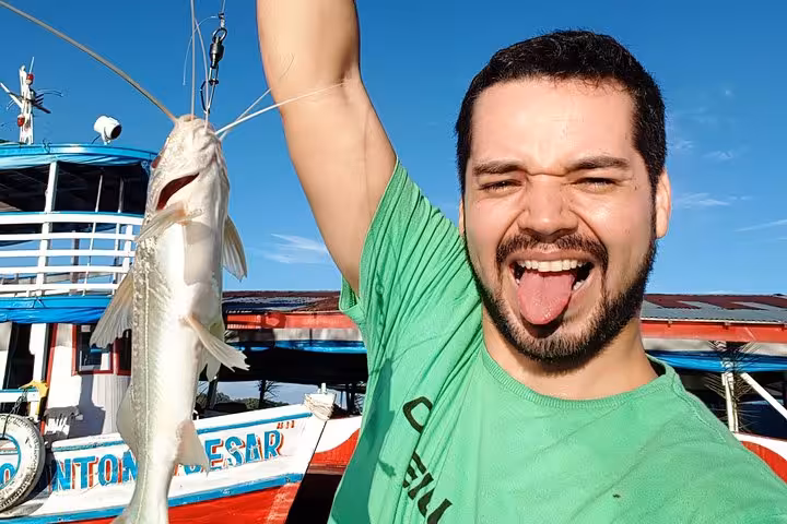 Traveler holding a freshly caught Amazon catfish on the Manaus riverboat, part of a 4-day Amazon tour