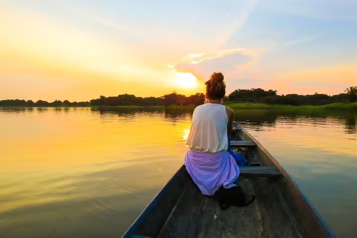 Woman enjoying a tranquil sunset boat ride on the Amazon River, a serene moment on the 5-day survival tour.