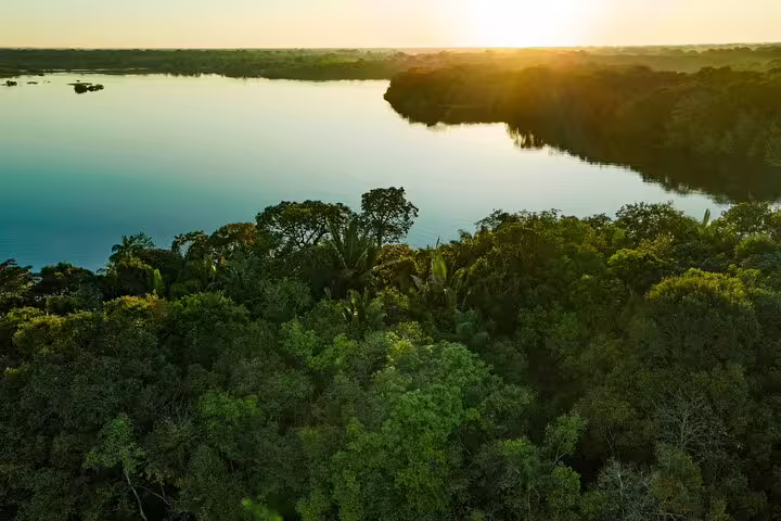 Stunning sunset over the Amazon River with dense rainforest in the foreground near Tapiri Floating Lodge.