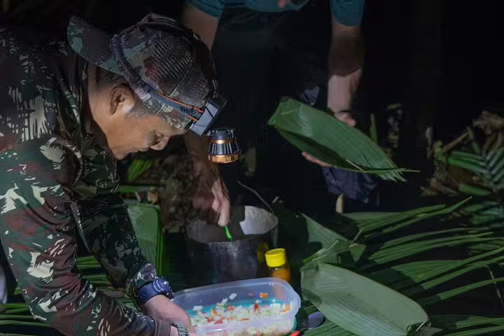 Tourist prepares a traditional meal under the guidance of a local expert during the Amazon Survival Tour.