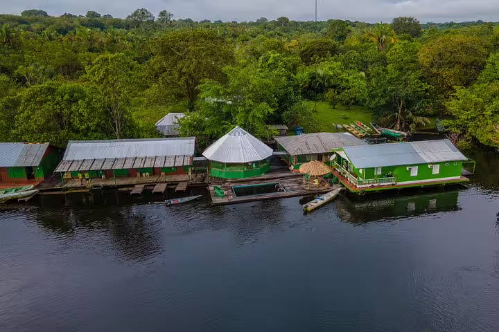 Aerial view of Amazon Tapiri Floating Lodge surrounded by lush greenery and calm river waters in the Amazon rainforest.
