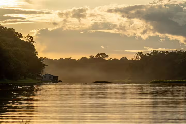 Serene sunset view over Amazon River near Tapiri Floating Lodge, highlighting lush jungle and tranquil waters.