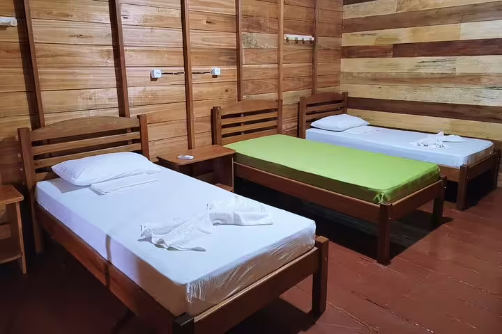 Three-bed setup in a wooden room at Amazon Tapiri Floating Lodge, ideal for family or group stays.