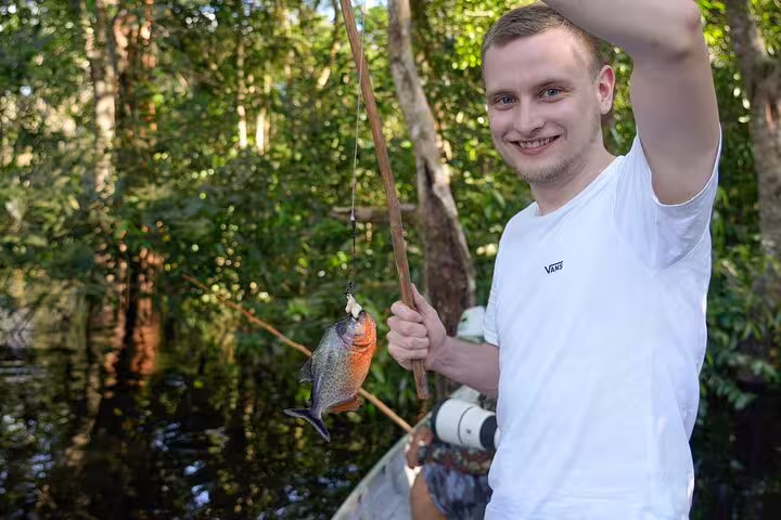 Traveler with a freshly caught fish in the Amazon River, highlighting adventure and fishing at Amazon Tapiri Lodge.